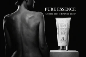 A sleek tube of Sisley Paris Energizing Foaming Exfoliant for the Body displayed on a white marble shelf.