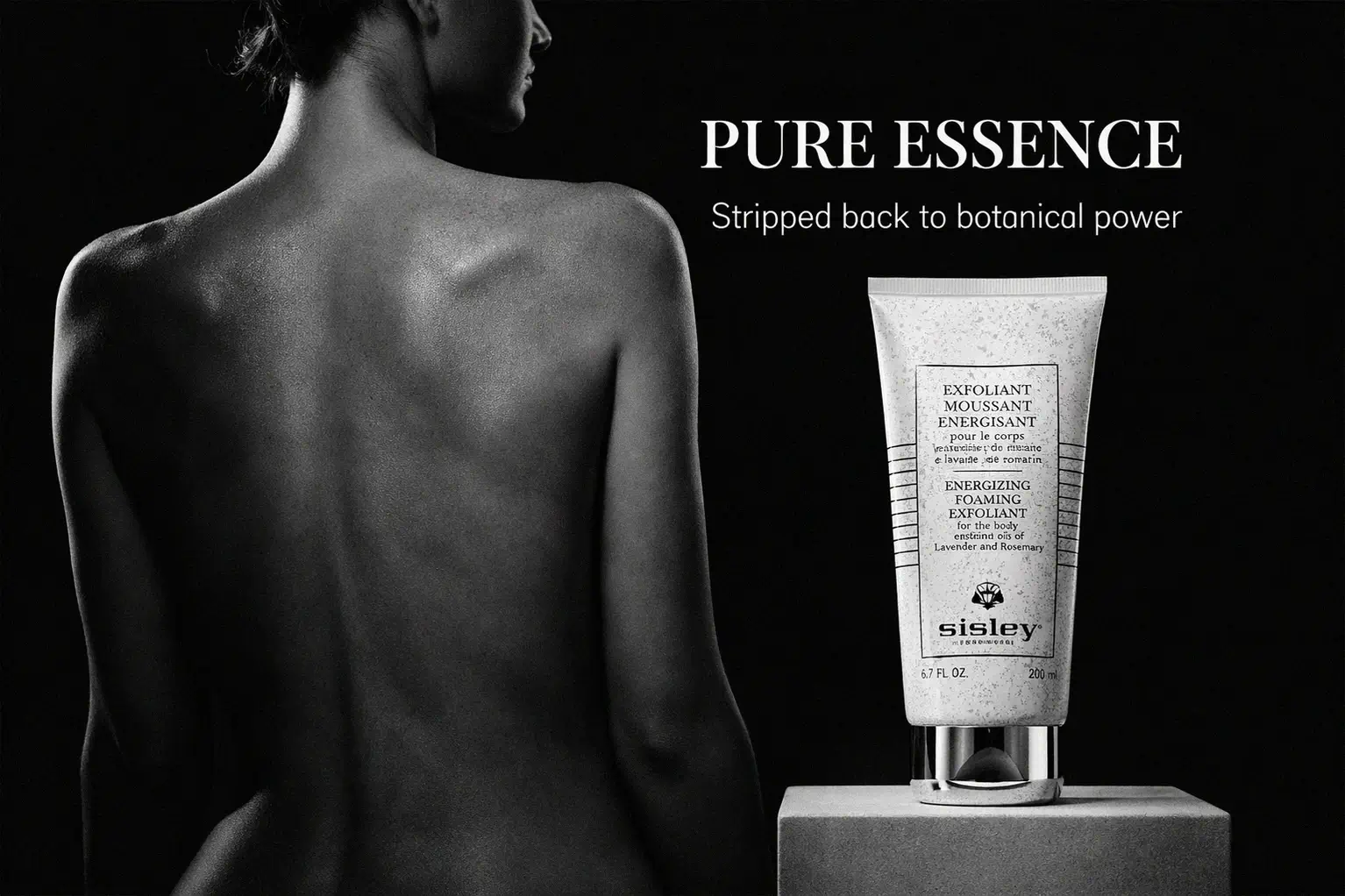 A sleek tube of Sisley Paris Energizing Foaming Exfoliant for the Body displayed on a white marble shelf.