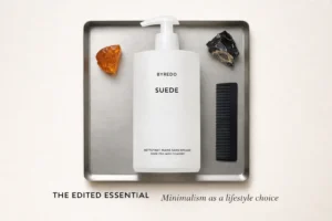 A minimalist Byredo Suede 450 ml velvet-matte white pump bottle on a marble bathroom vanity.