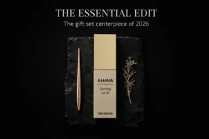 A sleek tube of AHAVA Glossing Lip Oil with a soft curved applicator shown on a clean vanity.