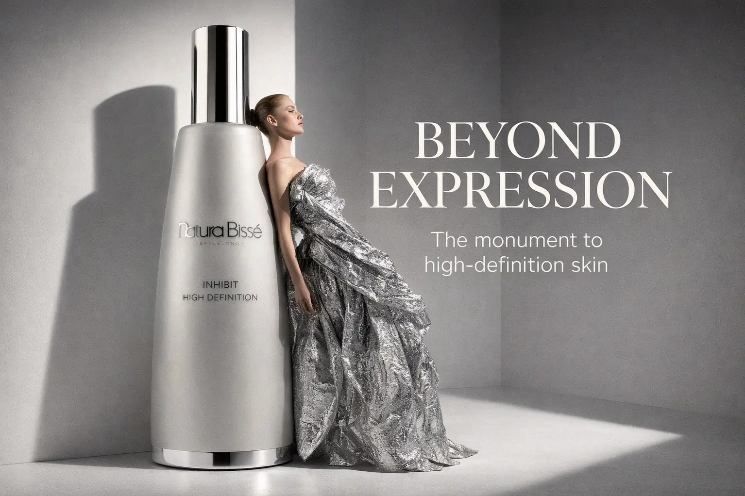 Silver and white bottle of Natura Bisse Inhibit High Definition Serum on a polished vanity surface.