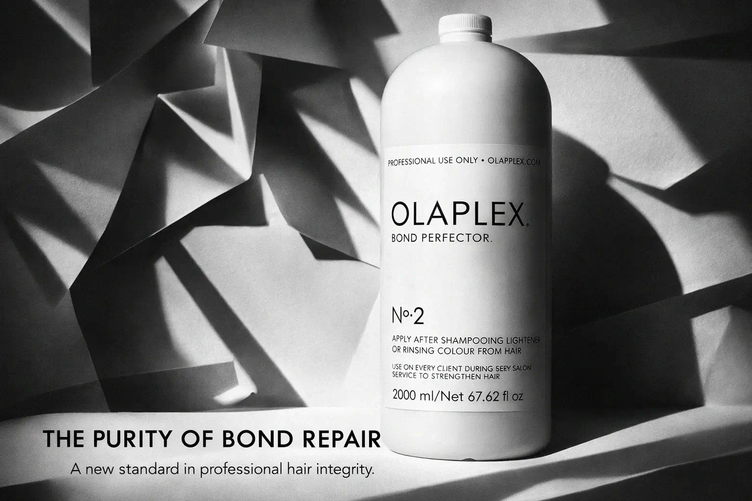 Large white bottle of Olaplex No. 2 Bond Perfector on a clean marble vanity with a minimalist aesthetic.