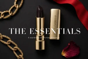 Gold-toned Dolce & Gabbana lipstick tube with intricate Mediterranean motifs on a white polished surface.