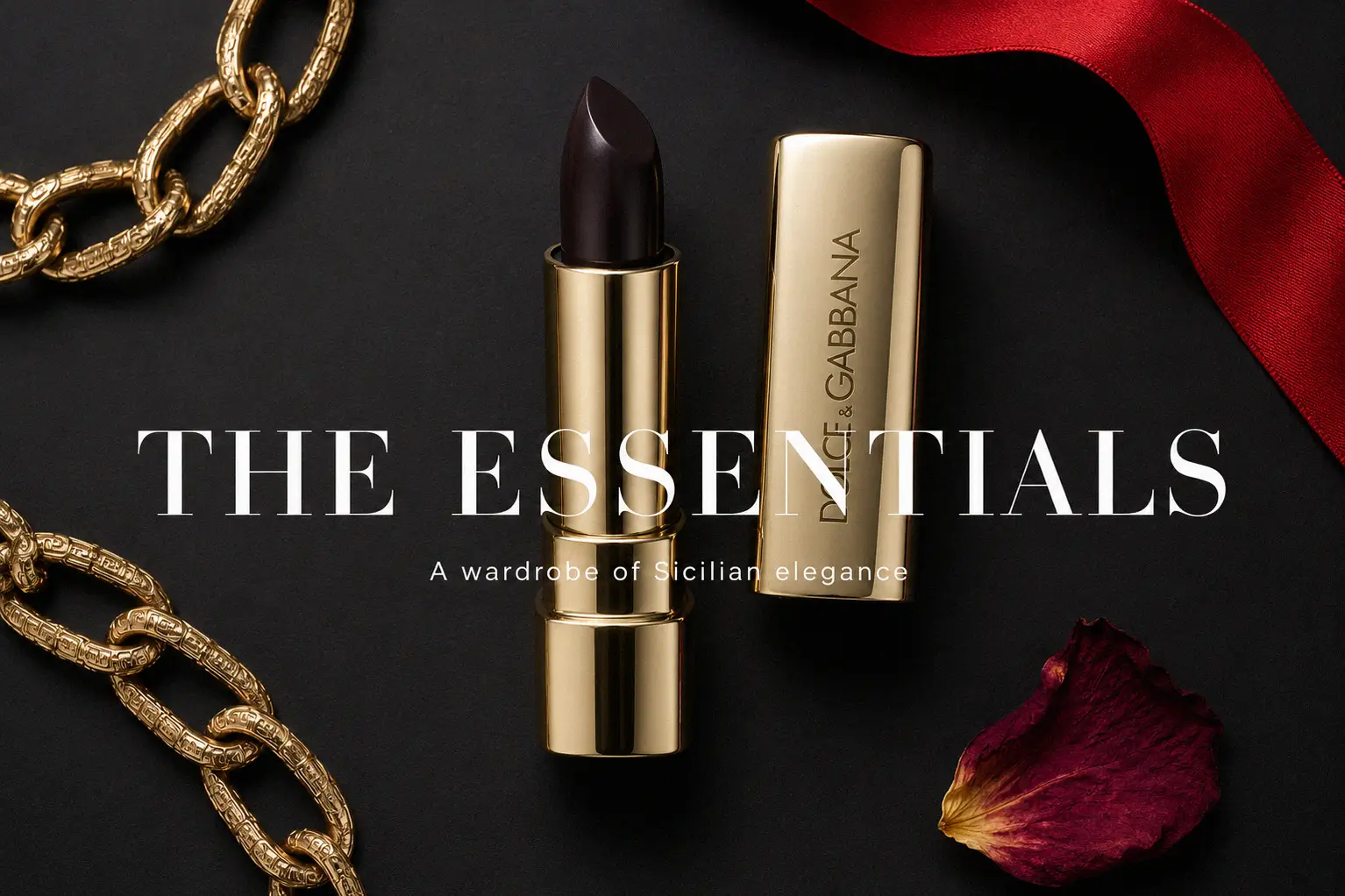 Gold-toned Dolce & Gabbana lipstick tube with intricate Mediterranean motifs on a white polished surface.