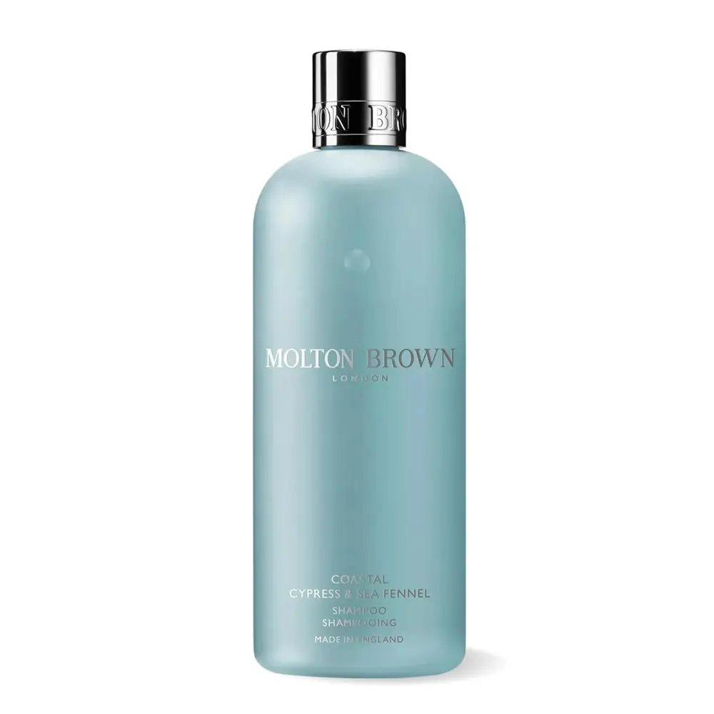 A bottle of Molton Brown Coastal Cypress & Sea Fennel Shampoo on a marble vanity