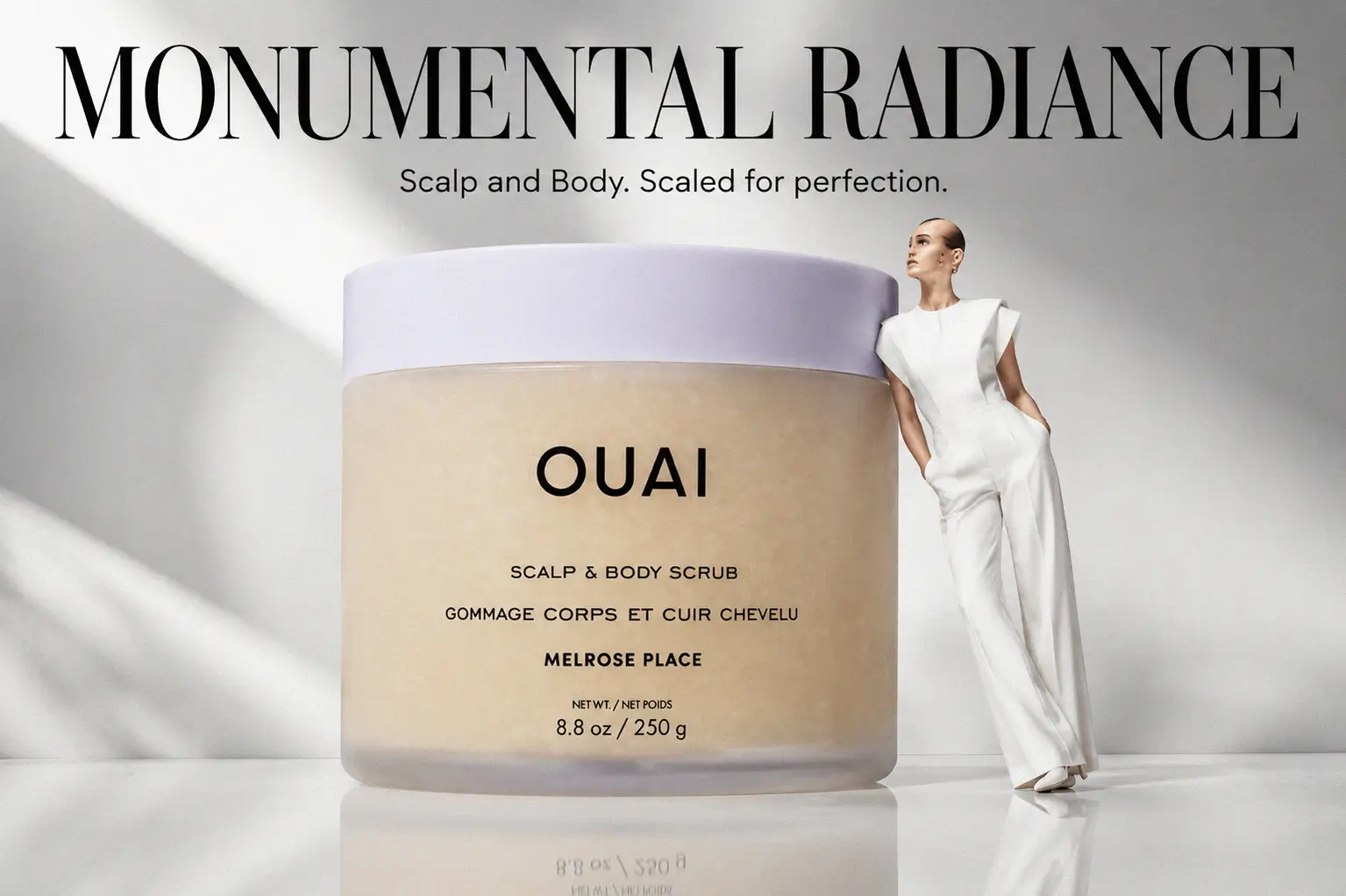 A jar of Ouai Scalp & Body Scrub sitting on a marble bathroom counter with soft lighting.
