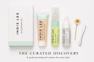 Three travel-sized Indie Lee skincare bottles including Brightening Cleanser and CoQ-10 Toner on a white surface.