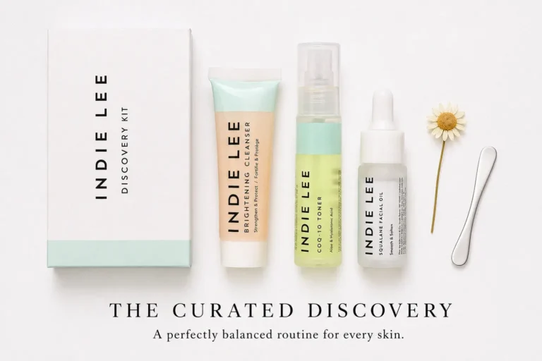 Three travel-sized Indie Lee skincare bottles including Brightening Cleanser and CoQ-10 Toner on a white surface.
